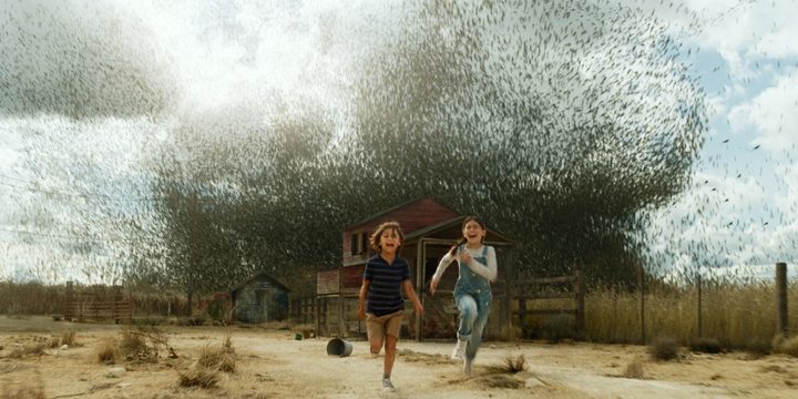 Two children run from a swarm of locusts in a scene from Jurassic World Dominion.