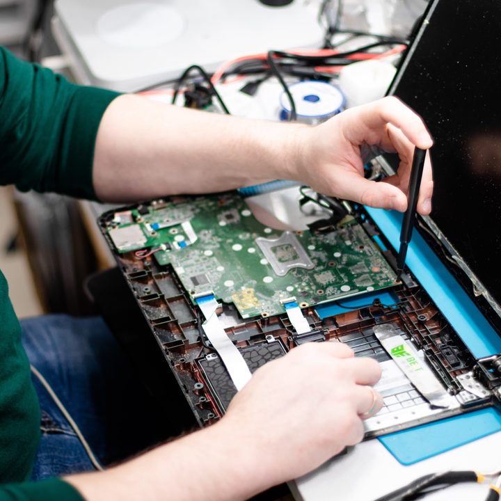 Someone repairing the inside of a MacBook with a small screwdriver.