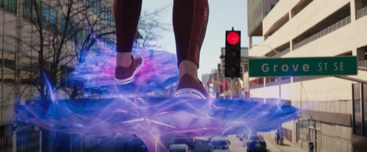 Ms. Marvel taps her foot while standing on a platform of energy in front of a traffic light.