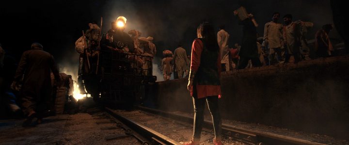 Ms. Marvel stands on a crowded train station's track in a scene from the series.