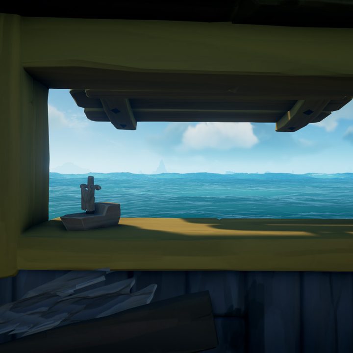 A small window on a sloop, gazing out to sea, with a wooden boat decoration placed.