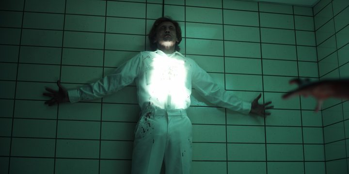 A rift forms in the middle of a character who's held against the wall i a scene from Stranger Things.