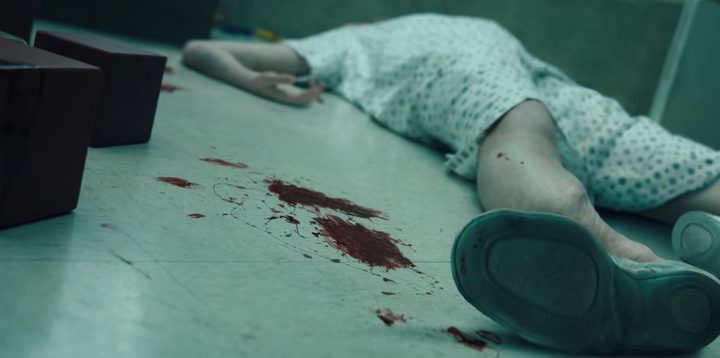 A body lies broken and bloody on the floor of a lab in a scene from Stranger Things season 4.