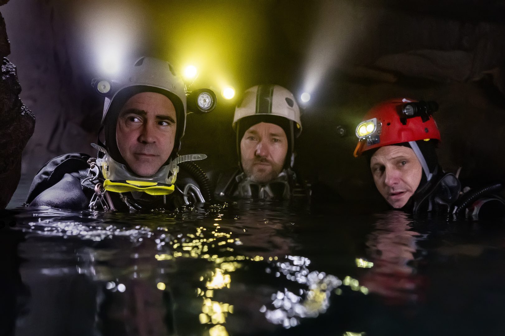 Colin Farrell, Joel Edgerton, and Viggo Mortenson stand in the water in a scene from Thirteen Lives.