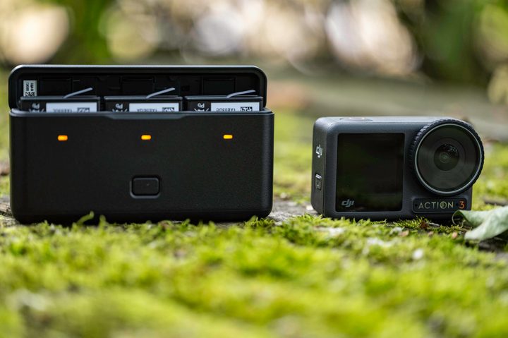 The DJI Osmo Action 3 and multifunction battery case on a mossy picnic table.