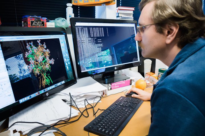 A researcher looks at a protein diagram on his monitor