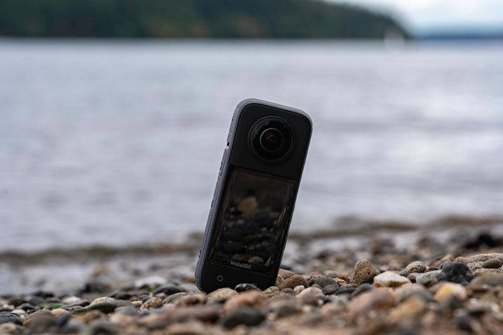 The Insta360 X3 on a pebble beach next to the sea.