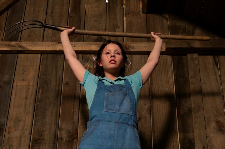 Mia Goth holds a pitchfork over her head in A24's Pearl.