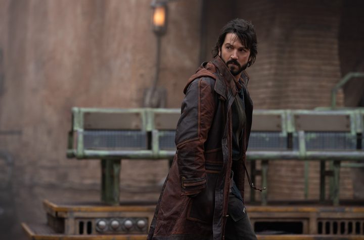 Diego Luna looks behind him while walking down a street in a scene from Andor.