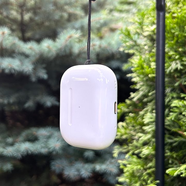 Apple AirPods Pro 2 charging case suspended from its lanyard loop.