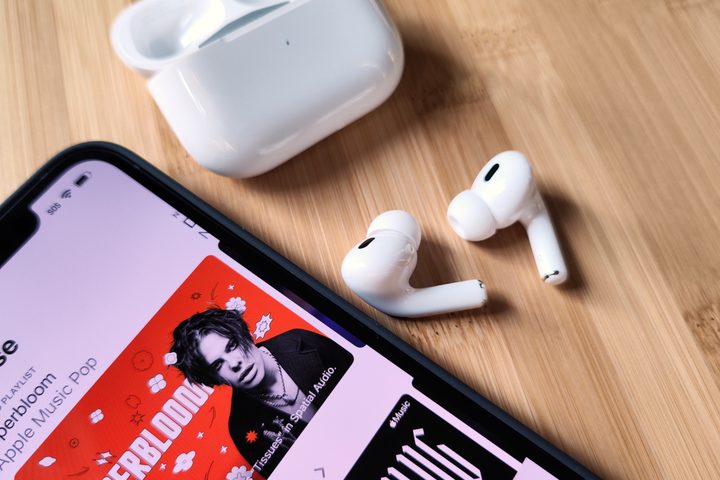 Apple AirPods Pro 2 sitting beside iPhone 14 and charging case.