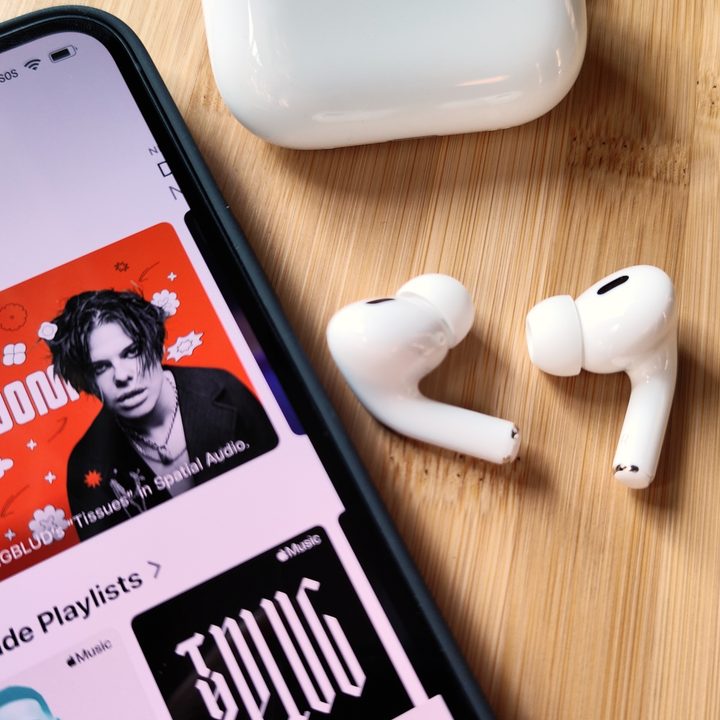 Apple AirPods Pro 2 sitting beside iPhone 14 and charging case.