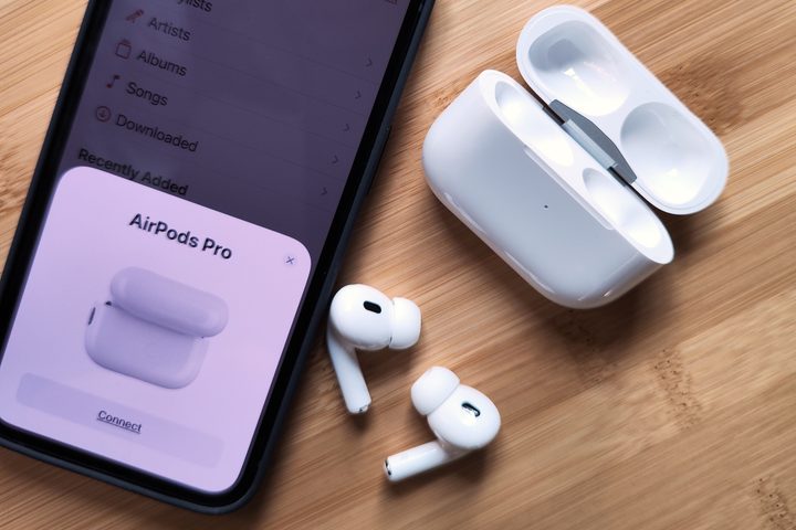 Apple AirPods Pro 2 sitting beside iPhone 14 and charging case.