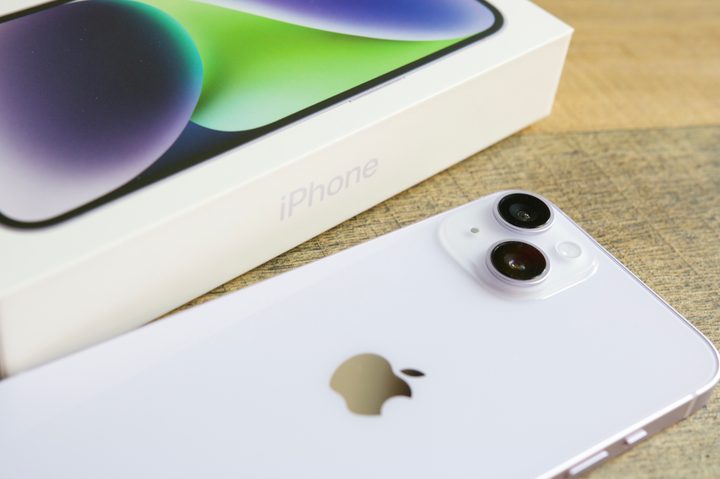 An iPhone 14 laying next to its retail box.