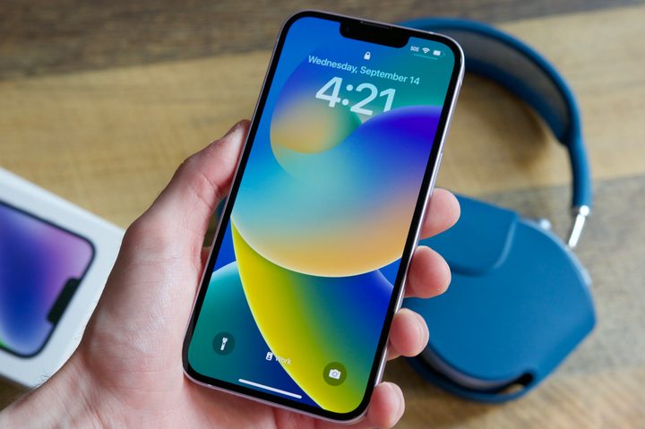 Someone holding an iPhone 14, showing the Lock Screen.