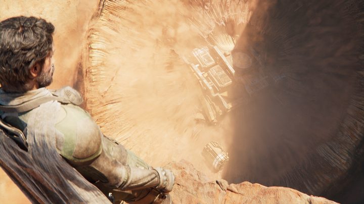 A man looking down at a massive sand pit.