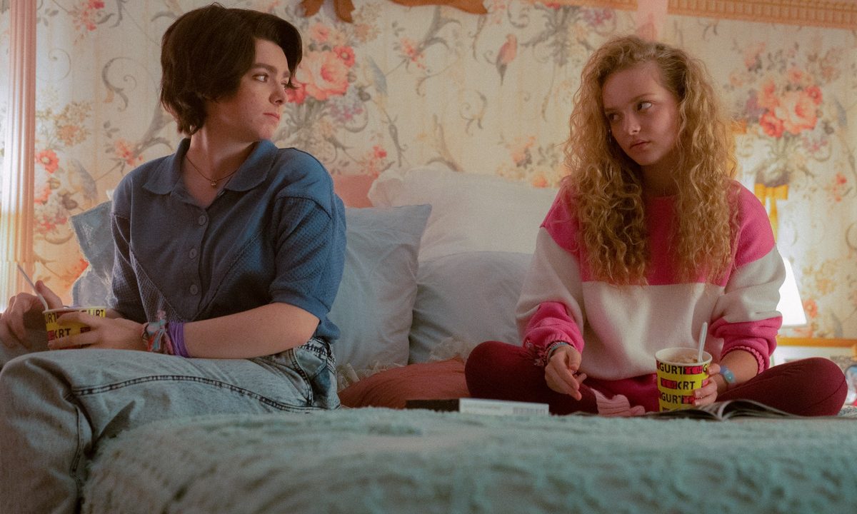 Elsie Fisher and Amiah Miller sit on a bed in a scene from My Best Friend's Exorcism.