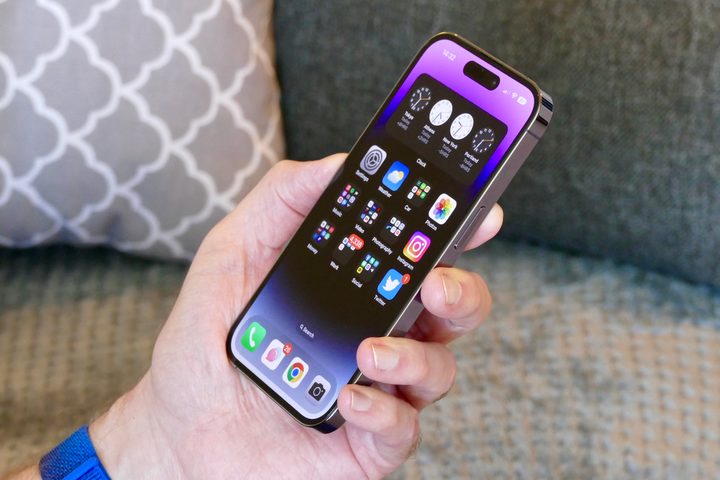 The iPhone 14 Pro held in a mans hand showing the screen.