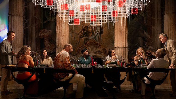 Guests talks at a dinner table in Knives Out 2.