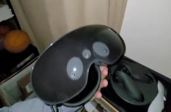 The black meta quest pro taken out of its box and held in a hand