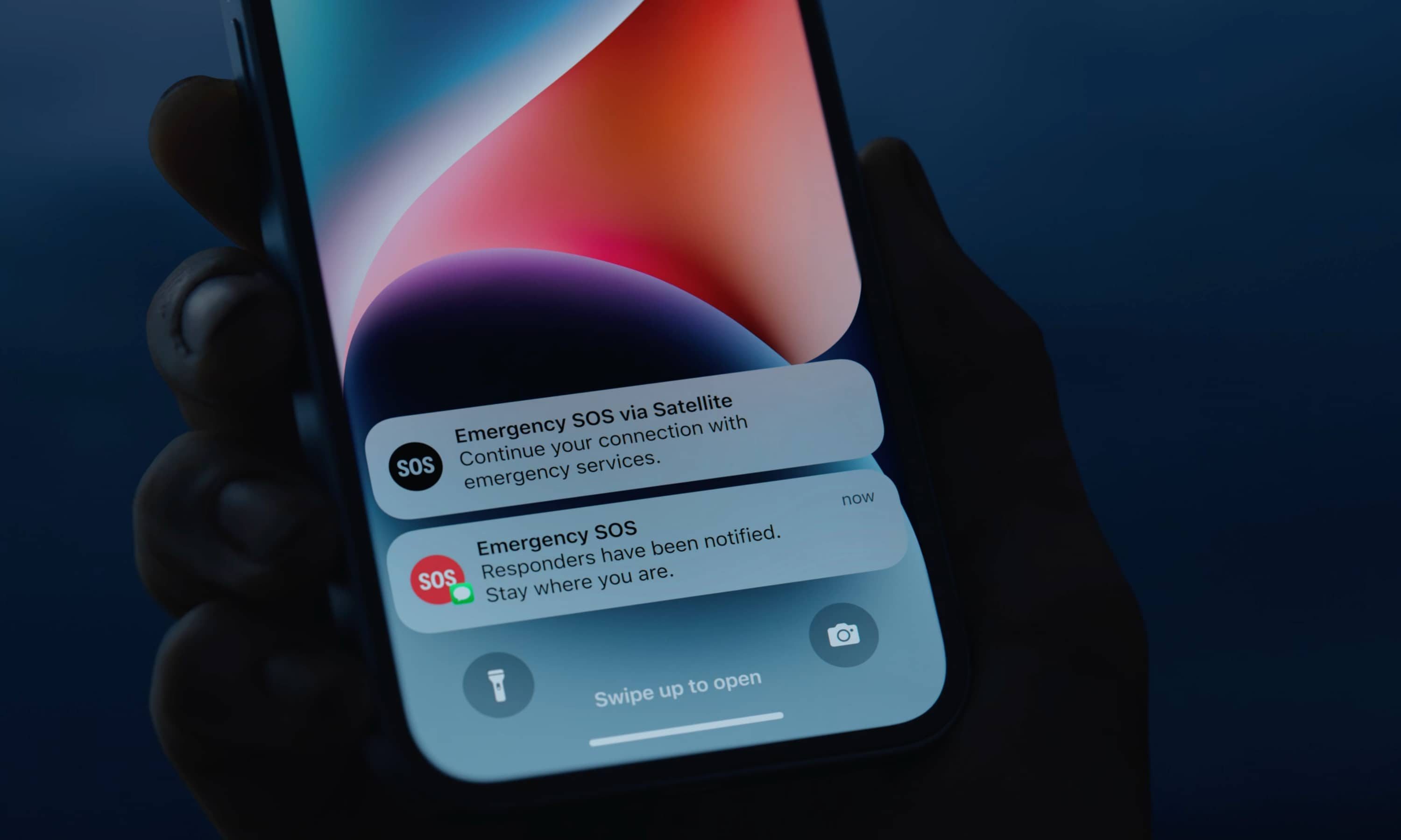 Person holding iPhone 14 with Emergency SOS via satellite notifications.