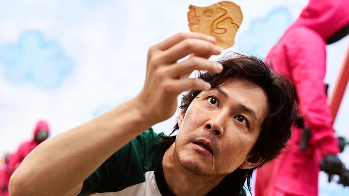 Seong Gi-hun from Squid Game looking at the honeycomb candy in a scene from "Squid Game."