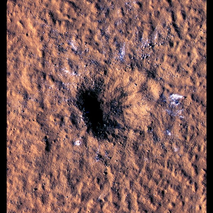 Boulder-size blocks of water ice can be seen around the rim of an impact crater on Mars.