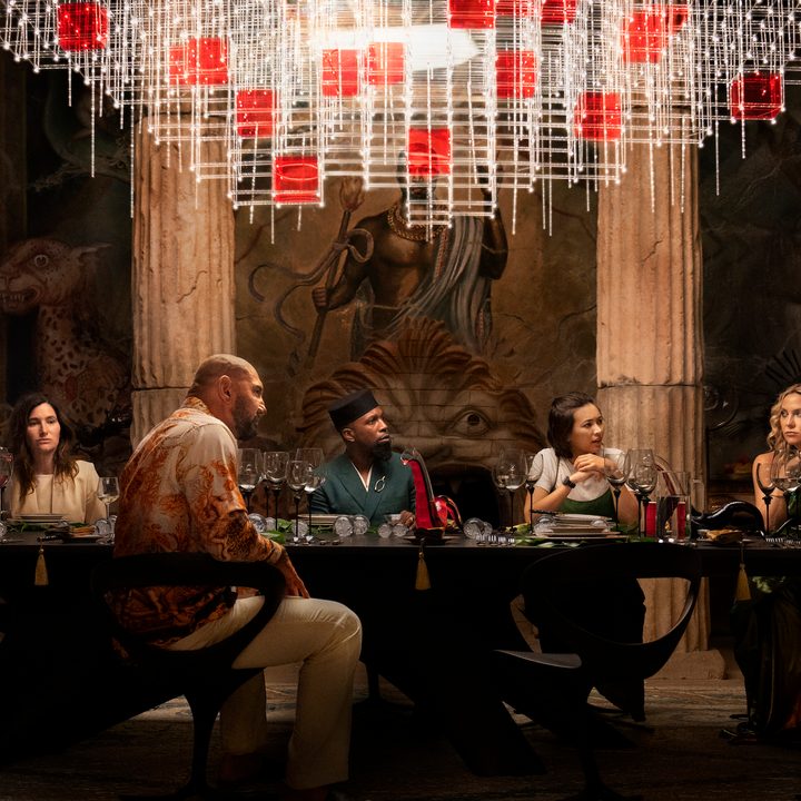 The cast of Glass Onion gather around a table in a scene from the Netflix film.
