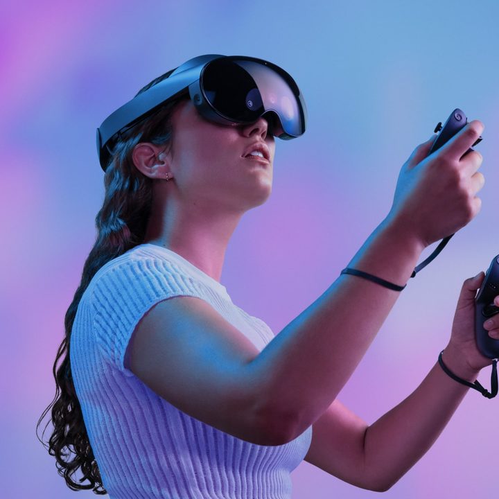 A model poses with a Meta Quest Pro over a colorful background.