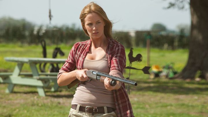 Sara holding a rifle and staring at something off-camera in Looper.