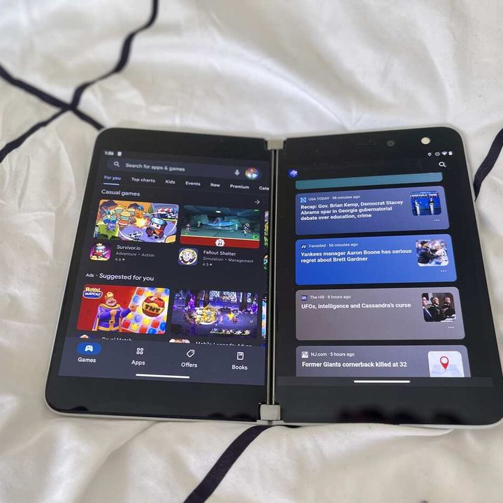 A Microsoft Surface Duo sitting on a bed.