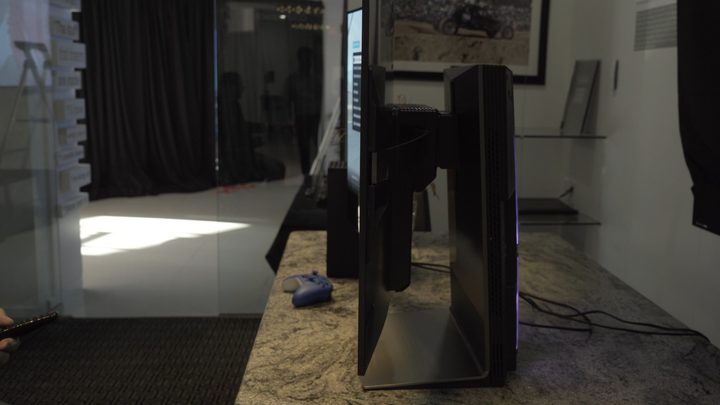 Profile of LG Flex OLED flexible TV with game console controller and remote control in background