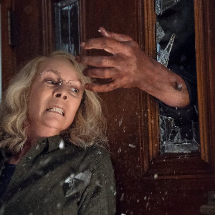 Michael Myers breaks his hand through a glass door in Halloween (2018)
