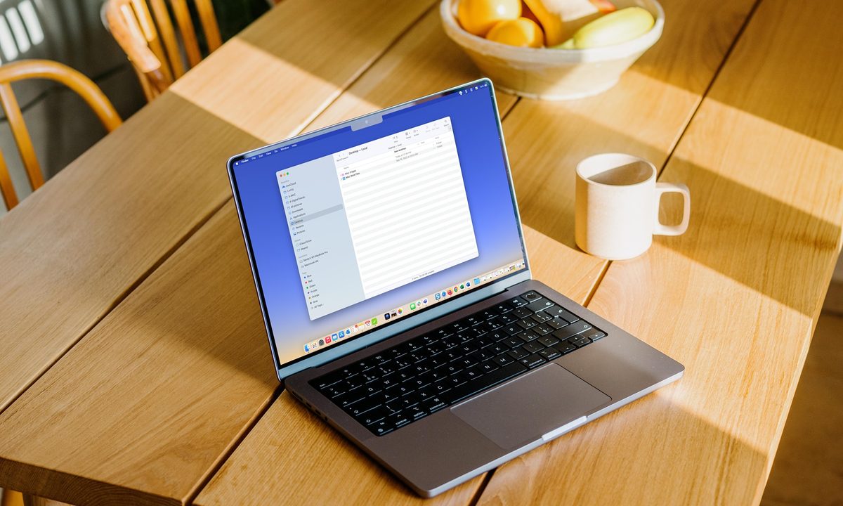 MacBook on a table with the Finder sidebar open.