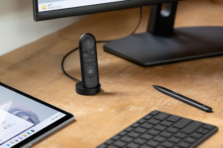 The Microsoft Presenter+ remote stood on a desk next to a keyboard and monitor.