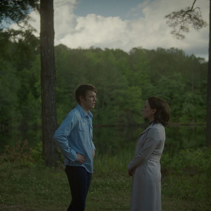 Jake Lacy and Anna Paquin stand together and talk in a scene from A Friend of the Family.