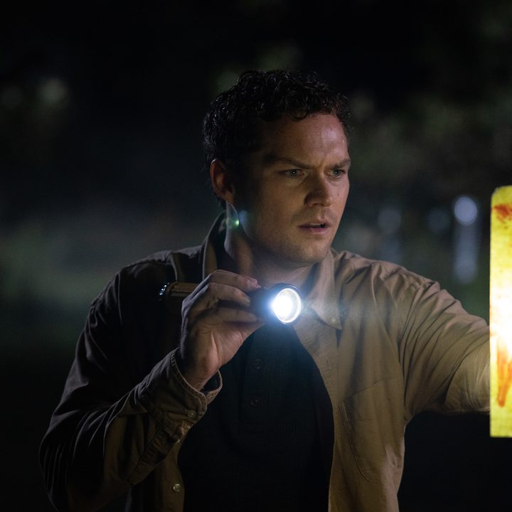 Finn Jones holds a flashlight in a scene from The Visitor.