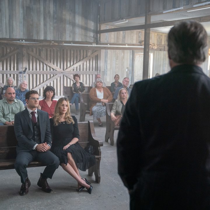 Finn Jones and Jessica McNamee sit in a church pew in a scene from The Visitor.