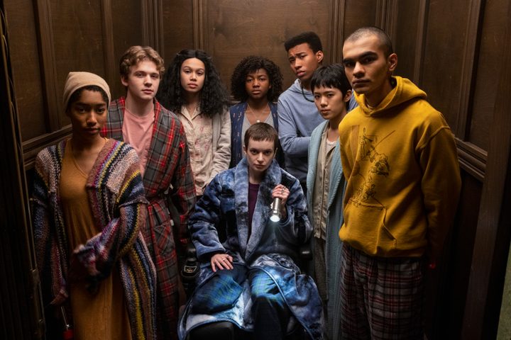 The members of The Midnight Club all stand in an elevator together.