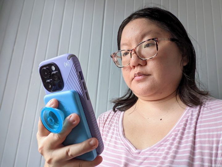 Christine Romero-Chan using her iPhone 14 Pro with an Anker PopSocket battery pack attached