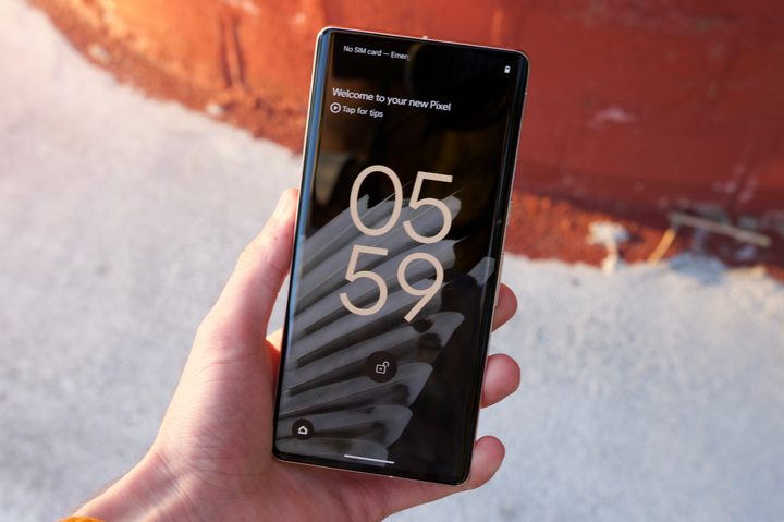 Holding the Pixel 7 Pro. The display is on and showing the Lock Screen.
