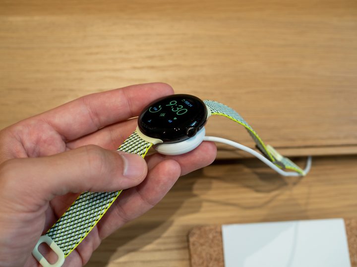 Google Pixel Watch with a recycled loop strap on its charger.