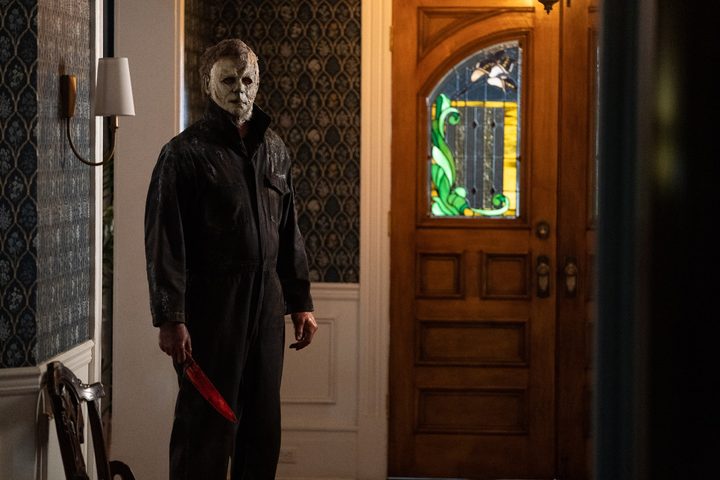 Michael Myers stares at the camera from the hallway of a house in a scene from Halloween Ends.