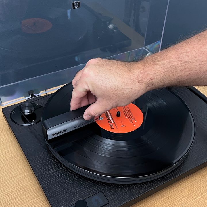 Placing an anti-static brush on the record at the nine o'clock position.