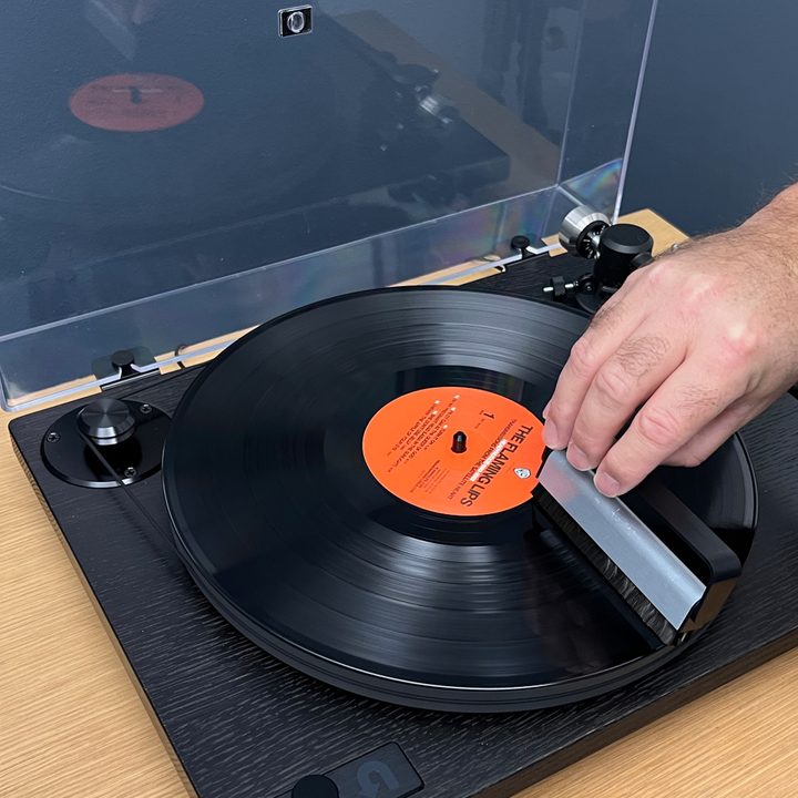 Placing the anti-static brush on the record at the six o'clock position.