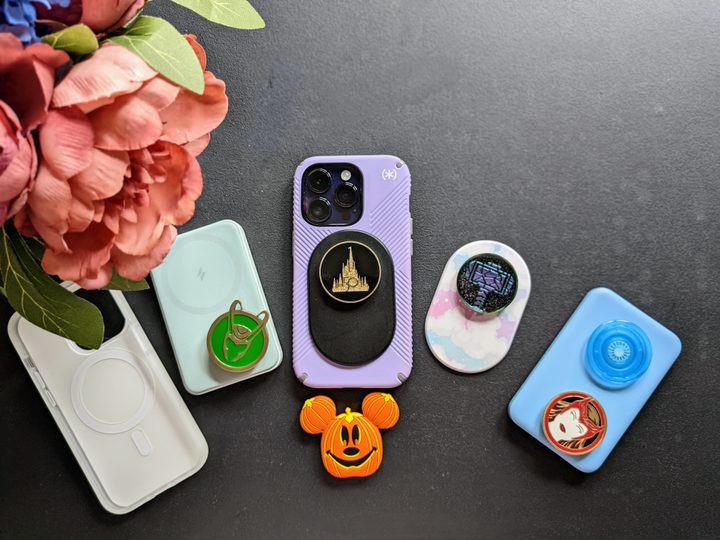 iPhone 14 Pro with Speck MagSafe Presidio Grip case on, with a black PopSocket MagSafe with Walt Disney World 50th Celebration PopSocket, along with a collection of MagSafe battery packs and PopTops