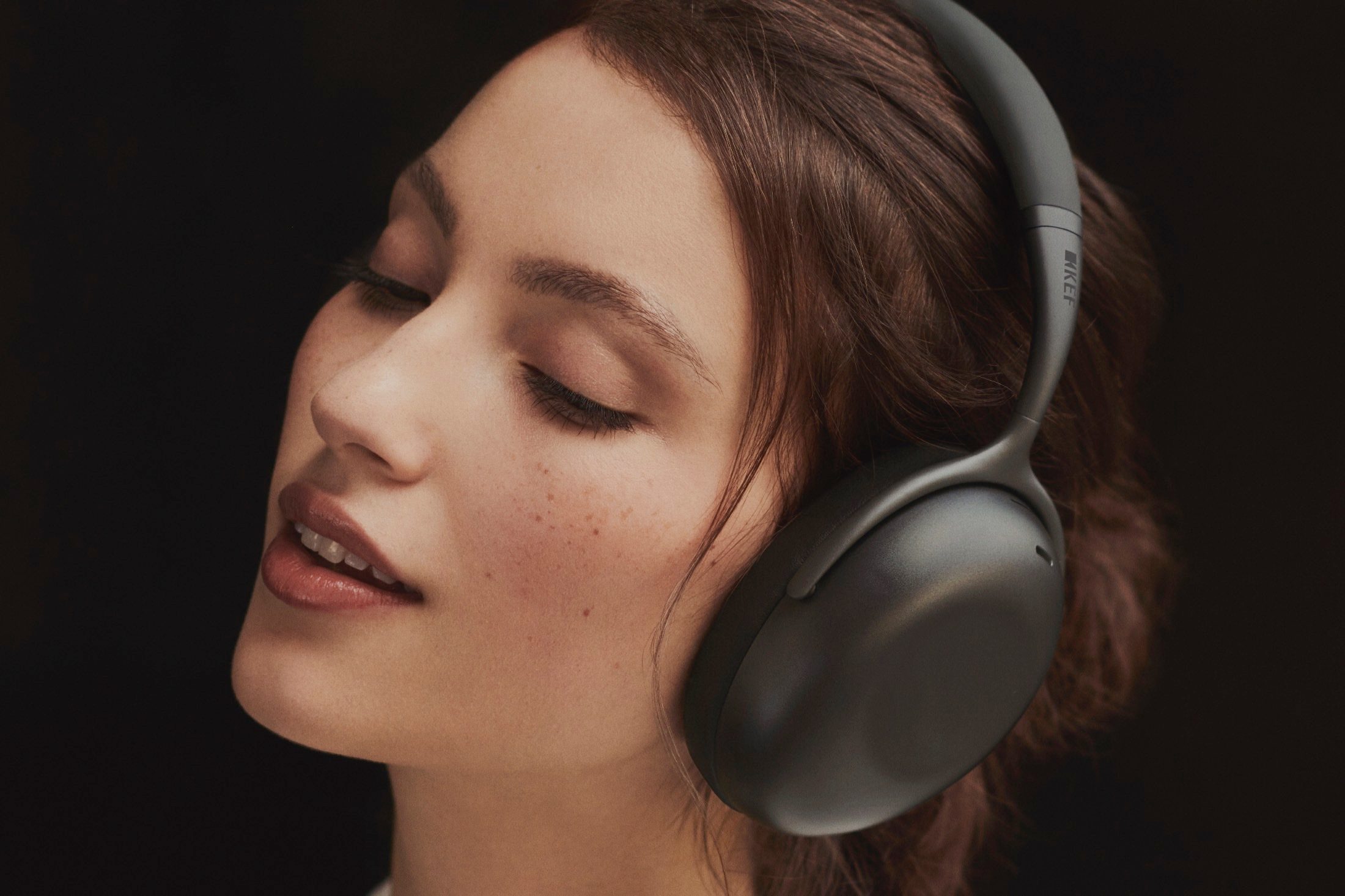 Woman wearing KEF Mu7 wireless noise-canceling headphones.