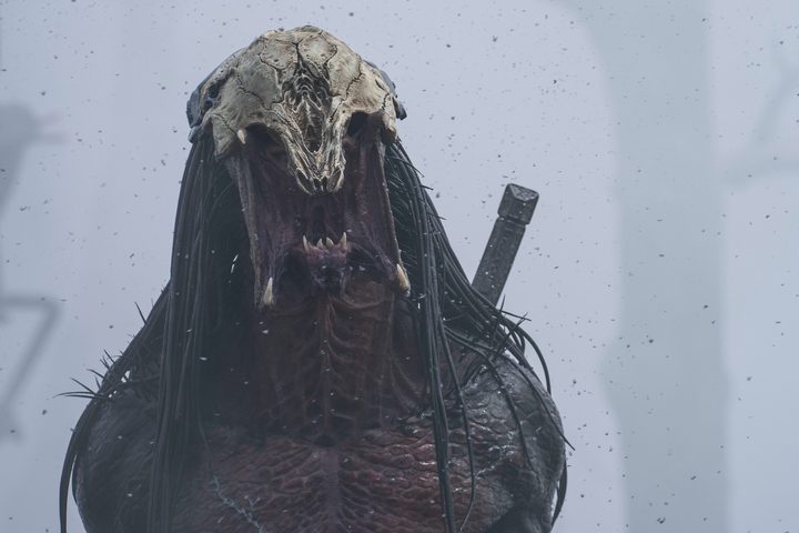 The PRedator alien roars against a gray fog in the background.