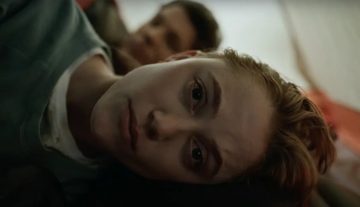 Maika Monroe stares at the camera while lying down.