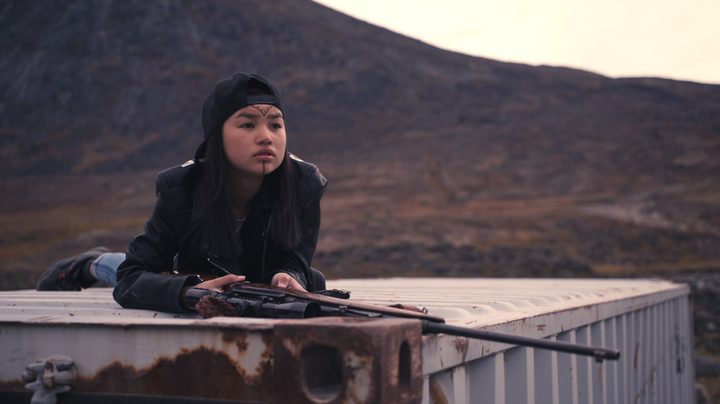 Tasiana Shirley sits on top of a shipping container with a rifle in a scene from Slash/Back.